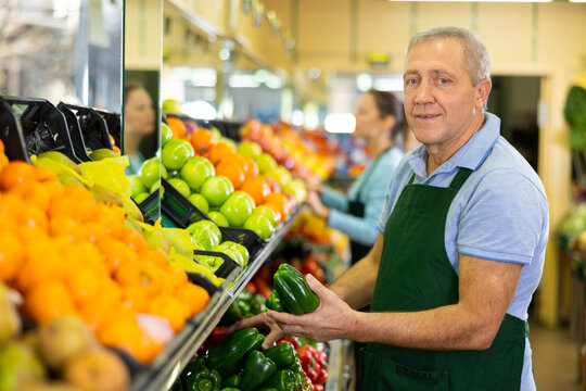 male seller of vegetable shop chooses fresh and ripe onion for regular customer