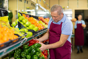 male seller of vegetable shop chooses fresh and ripe onion for regular customer