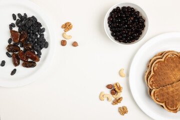 Waffles, berries and dried fruits on a white table.