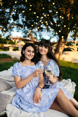 Naklejka premium Girls in dresses and hats on a picnic. Girls drink wine.