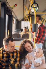 Happy parents and son riding in bus while baby sits in mother lap.