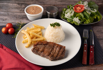Picanha grelhada, arroz branco, feijão e fritas acompanhado de salada de rúcula