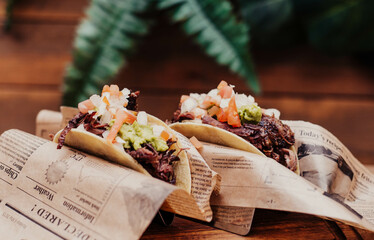 Tacos de puerco desmenuzado y verduras en mesa de madera
