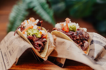 Tacos de puerco desmenuzado y verduras en mesa de madera
