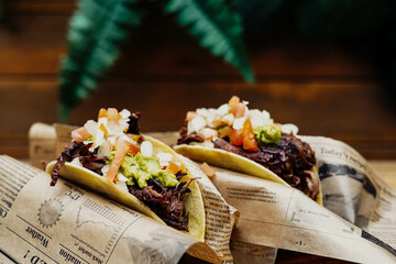 Tacos de puerco desmenuzado y verduras en mesa de madera

