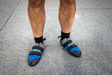 Close up of man's feet wearing indoor climbing wall shoes standing on soft flooring safety mat. 