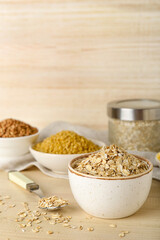 Bowl of raw oatmeal flakes on wooden table
