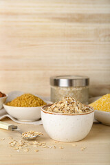 Fototapeta na wymiar Bowl of raw oatmeal flakes on wooden table