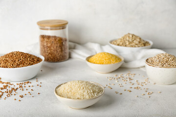Bowl with rice and different cereals on light background
