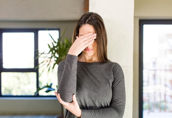 young adult pretty woman looking stressed, ashamed or upset, with a headache, covering face with hand