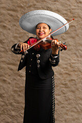 female mexican mariachi woman smiling playing violin, mariachi girl suit on a clay wall background....