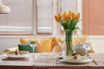 Table setting for International Women's Day celebration with tulip flowers and teapot in interior of room