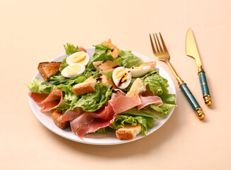 Plate of delicious salad with boiled eggs and jamon on beige background