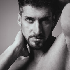 Portrait of a handsome young man with stylish haircut posing over gray background. Perfect body&skin. Studio shot.