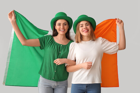 Young women with flag of Ireland on light background. St. Patrick's Day celebration