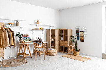 Interior of modern atelier with tailor's workplace, clothes and shelves