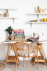 Interior of modern atelier with tailor's workplace, thread spools and shelves