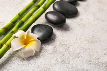 Fototapeta na wymiar Spa stones, flower and bamboo on light background