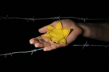 Woman with yellow Jewish badge and barbed wire on dark background. International Holocaust Remembrance Day - obrazy, fototapety, plakaty