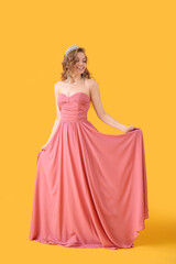 Young woman in tiara and prom dress on yellow background © Pixel-Shot