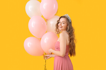 Young woman in prom dress with balloons on yellow background © Pixel-Shot