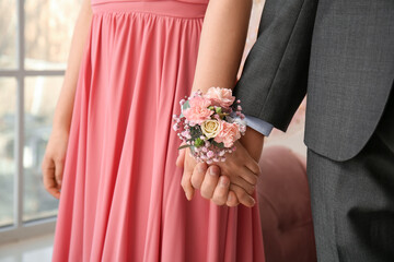 Young woman with corsage and her prom date holding hands, closeup