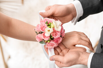 Young man tying corsage around his prom date's wrist, closeup