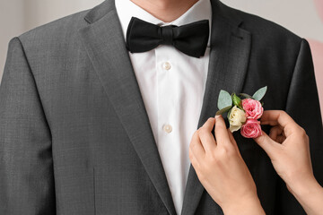 Young woman pinning boutonniere on her prom date's suit, closeup © Pixel-Shot