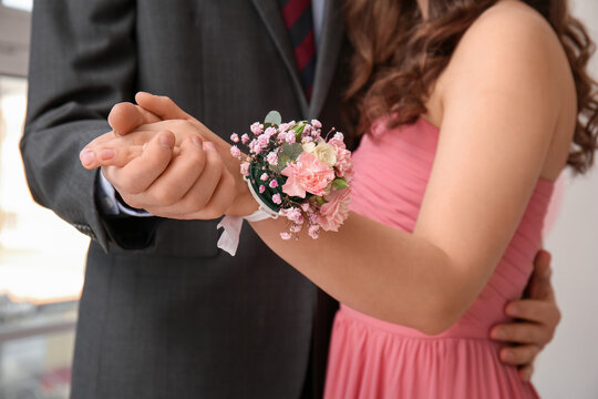 Young man and his prom date with corsage holding hands, closeup