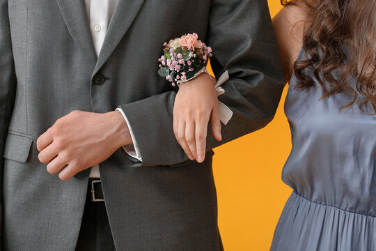 Young woman with corsage and her prom date on yellow background, closeup