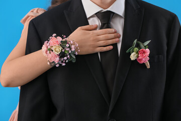Young woman with corsage hugging her prom date on blue background, closeup - obrazy, fototapety, plakaty