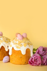 Easter cake, painted eggs and tulip flowers on yellow background