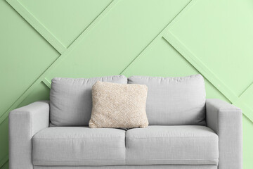 Stylish grey sofa near green wall