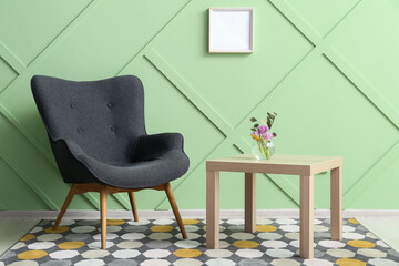 Modern grey armchair and table near green wall