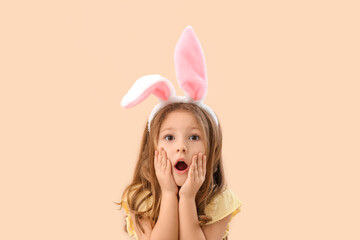 Obraz na płótnie Canvas Shocked little girl in bunny ears on beige background