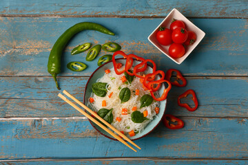 Plakat Composition with bowl of tasty rice noodles and vegetables on color wooden background