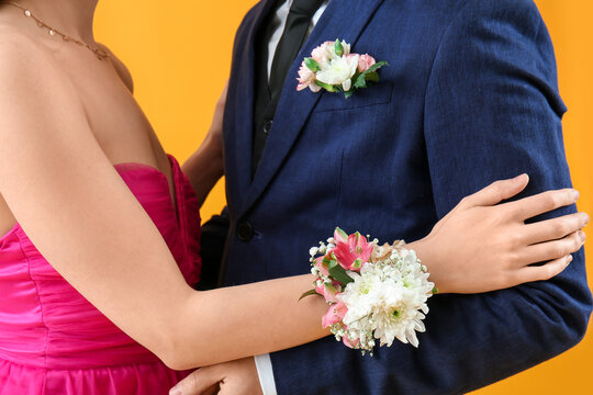 Young boy and his prom date dancing against yellow background, closeup