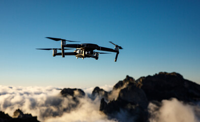 Drone with camera flying over the mountains.