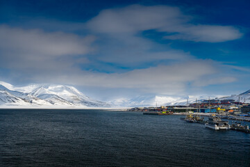 Naklejka premium 2022-05-09 THE SHORELINE WITH BEAUTIFUL SNOW COVERED MOUNTAINS AND SKY NEAR THE TOWN OF LONGYEARBEAN ON SVALBARD NORWAY IN THE ARCTIC