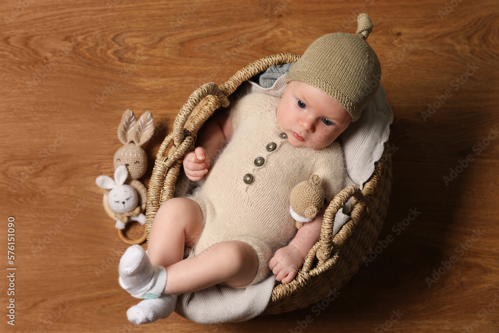 Wall mural Cute little baby with knitted bear toy in wicker basket, top view