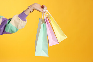 Woman holding shopping bags on yellow background, closeup. Big sale