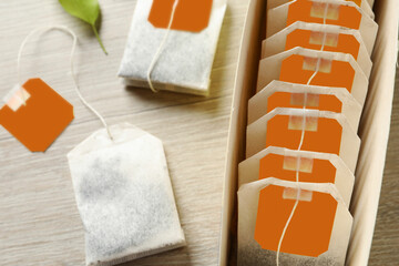 Box with paper tea bags on wooden table, closeup