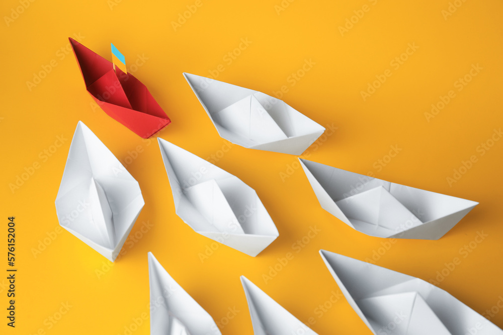 Poster Group of paper boats following red one on yellow background. Leadership concept