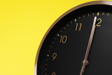 Closeup view of stylish round clock on yellow background, space for text. Interior element