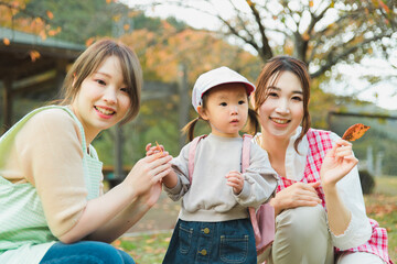 秋の公園を散歩・遠足する保育士の女性と園児（保育園・幼稚園保母）

