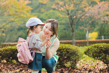 秋の公園を散歩・遠足する保育士の女性と園児（保育園・幼稚園保母）
