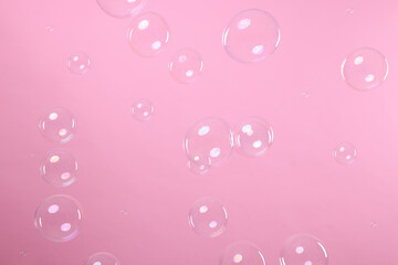Many beautiful soap bubbles on pink background