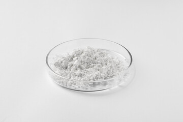 Petri dish with calcium carbonate powder on white background