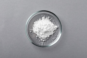 Petri dish with calcium carbonate powder on grey table, top view