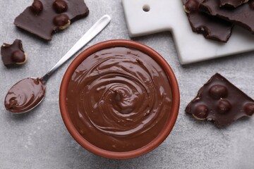 Chocolate pieces and bowl of sweet paste on grey table, flat lay
